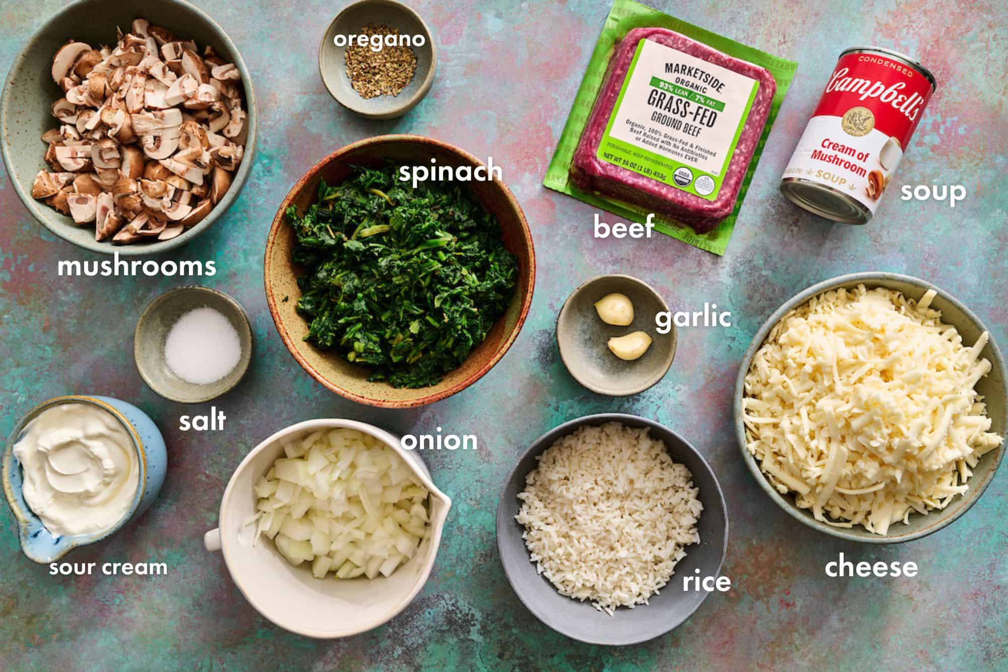 ingredients to make spinach ground beef casserole including rice, cheese, garlic, sour cream and mushrooms