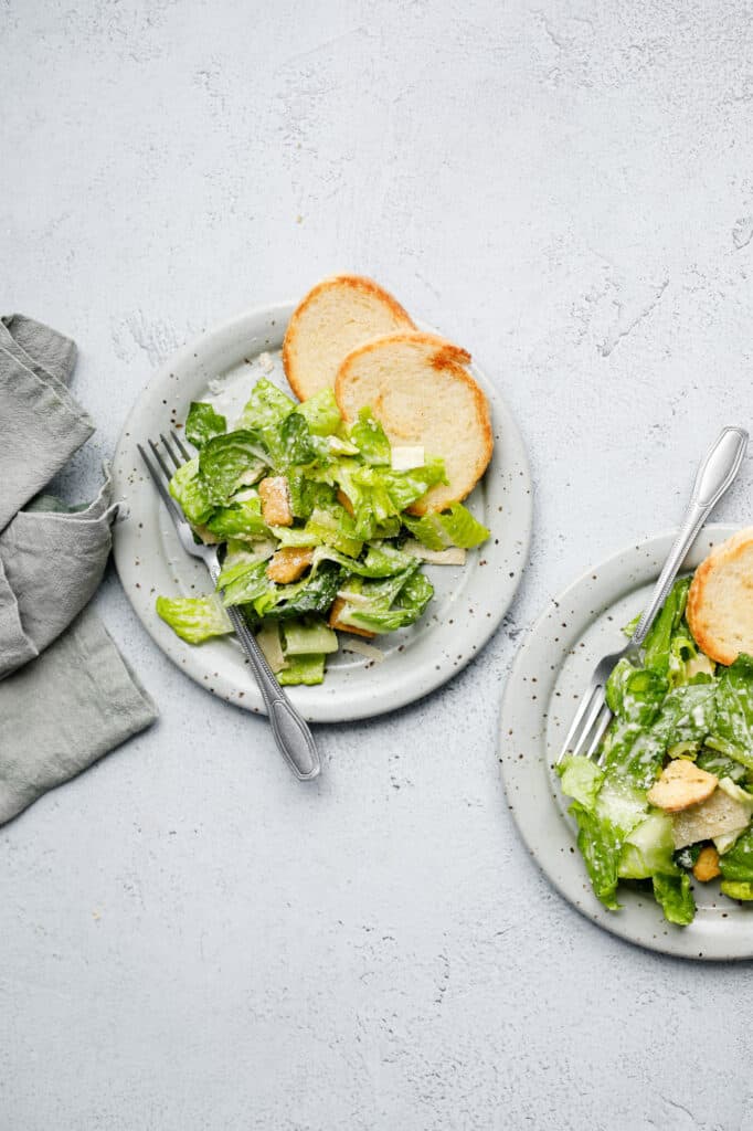 Overhead image of two plates of Salad on plates with forks and a napkin