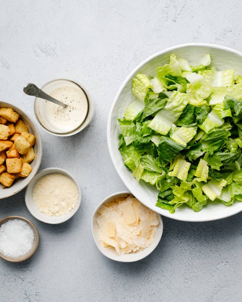 Components for homemade Caesar Salad seen overhead on a grey background