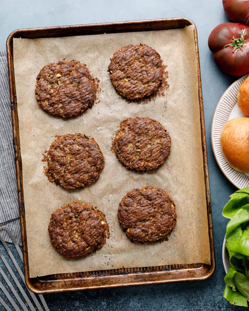 An overhead shot on a baking sheet with finished veggie burgers with their accompaniments on the side