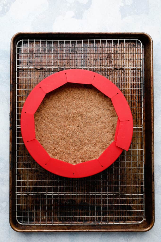 Overhead image of a pie crust on a baking rack with a silicone shield.