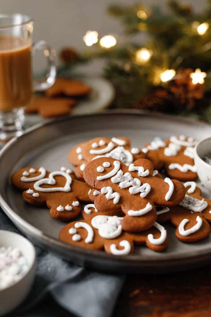 Gingerbread boys on a grey plate with silver sprinkles and sparkle lights in the background