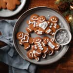 Overhead image of a plate of gingerbread cookies with holiday lights, sprinkles and a piping bag