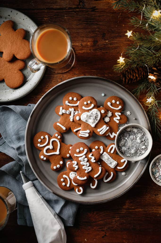 Overhead image of a plate of gingerbread cookies with holiday lights, sprinkles and a piping bag