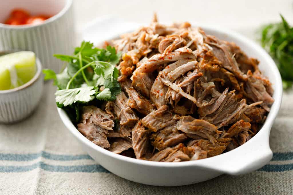 Pork Carnitas in a bowl with fresh cilantro and lime