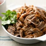 Pork Carnitas in a bowl with fresh cilantro and lime