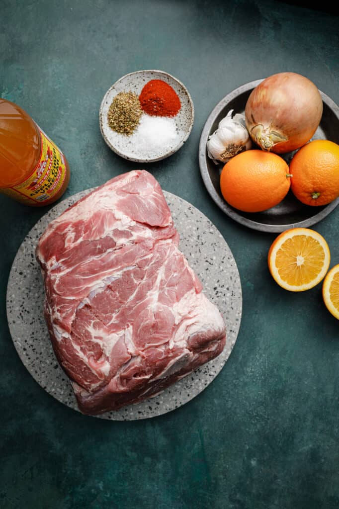 Ingredients for Instant Pot Pork Carnitas on a table with oranges, garlic and spices