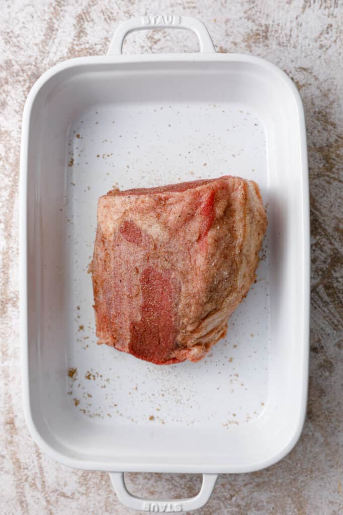 overhead image of a baking dish with an eye of round roast rubbed with spice blend, ready to be seared