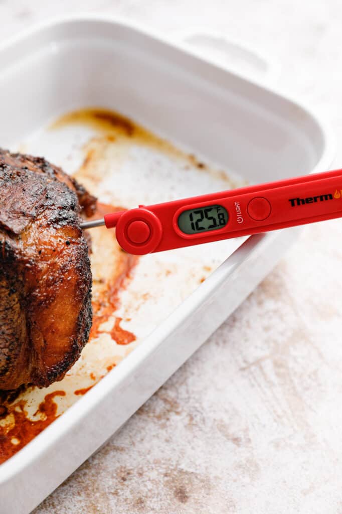 the beef out of the oven and showing a meat thermometer with 125F as the temperature