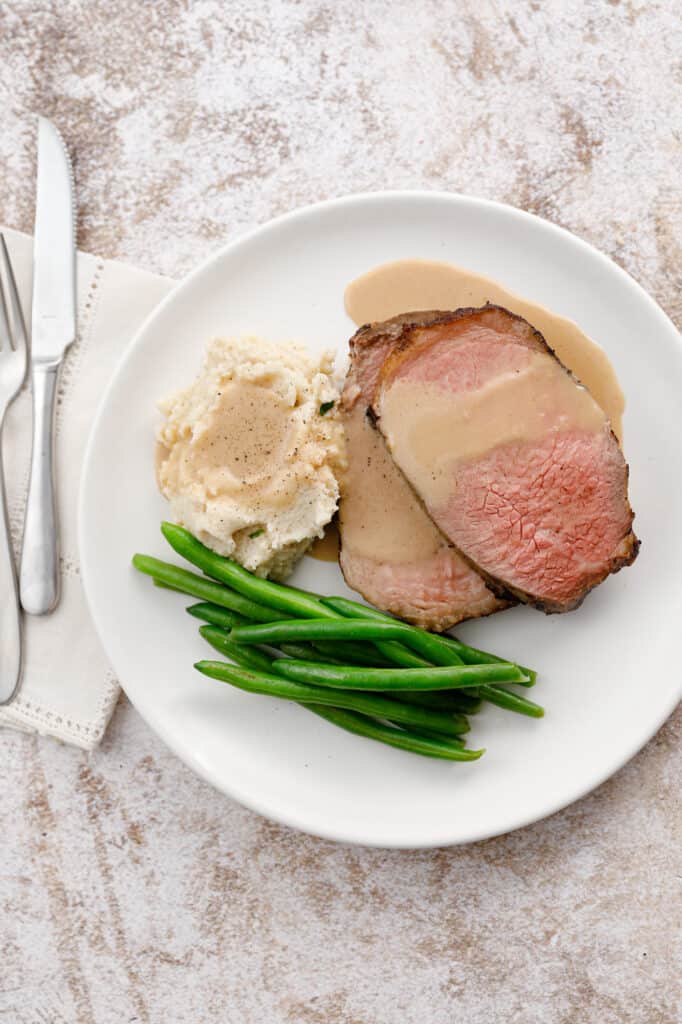 overhead shot of a plate of beef, mashed potatoes and green beans