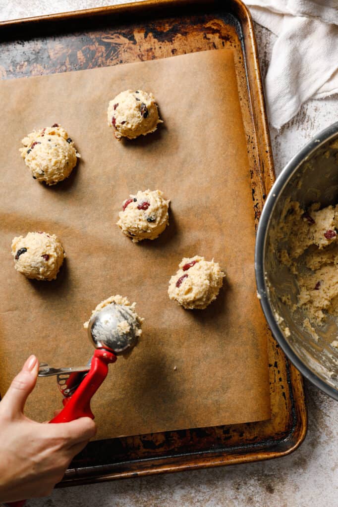 Scooping leftover oatmeal cookie dough onto a parchment sheet