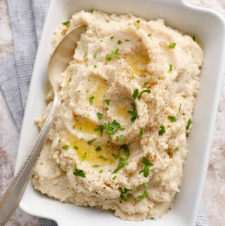 overhead view of a dish full of mashed cauliflower with pools of butter