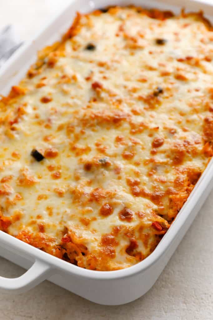 a casserole dish full of chicken and rice casserole topped with cheese, browned from baking in the oven