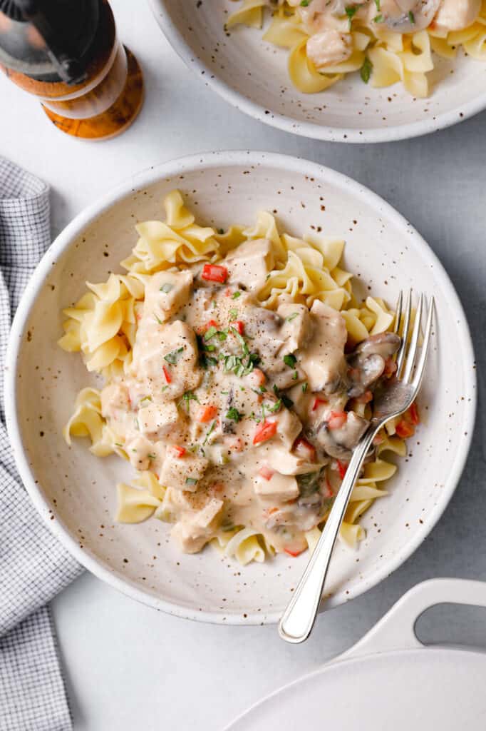 a bowl filled with Chicken a la King, creamy sauce with peppers and mushrooms over noodles