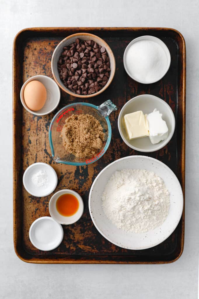 overhead view of all the ingredients to make classic chocolate chip cookies: butter, shortening, flour, sugar, brown sugar, vanilla, baking powder, salt, egg and chocolate chips