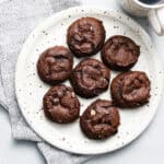 Chewy Chocolate Chocolate Chip Cookies on a white plate with a cup of coffee