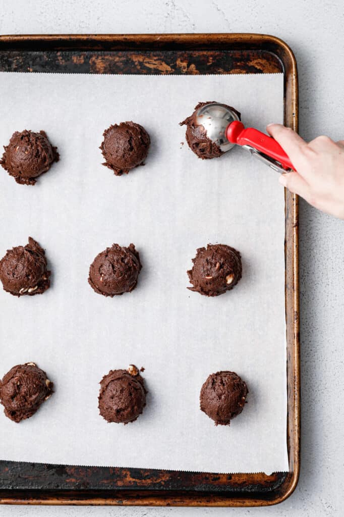 Scooping Chocolate Cookie Dough onto a baking sheet