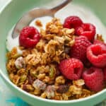 Side view of granola, berries and yogurt in a green bowl