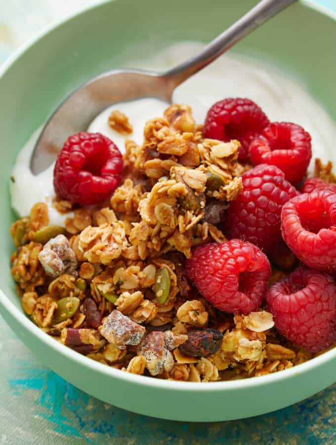 Side view of granola, berries and yogurt in a green bowl