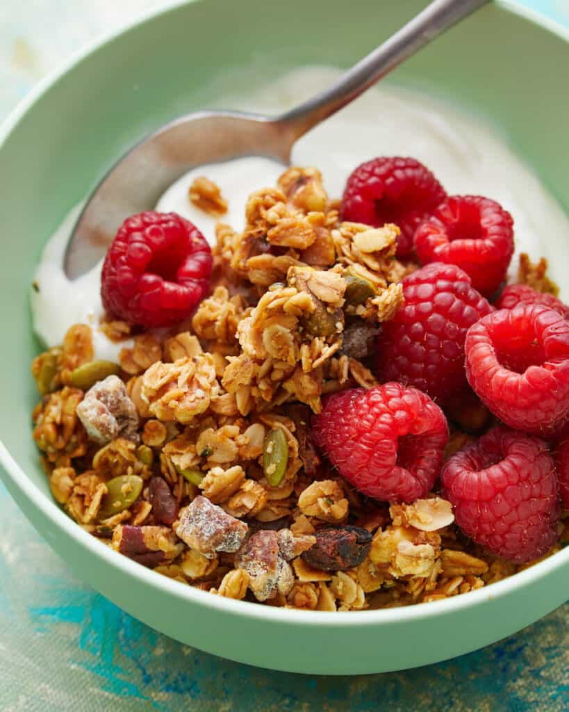 Side view of healthy homemade granola, berries and yogurt in a green bowl