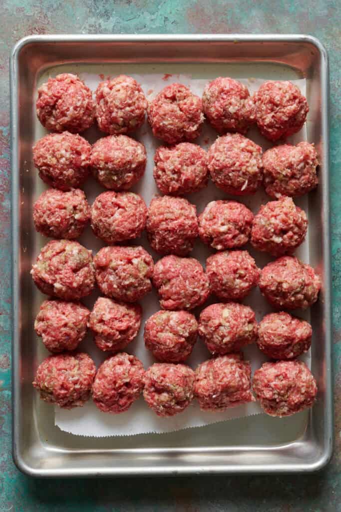 meatballs formed and placed on a sheet tray ready to be cooked