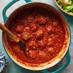 overhead view of meatballs in a red marinara sauce in a teal pot