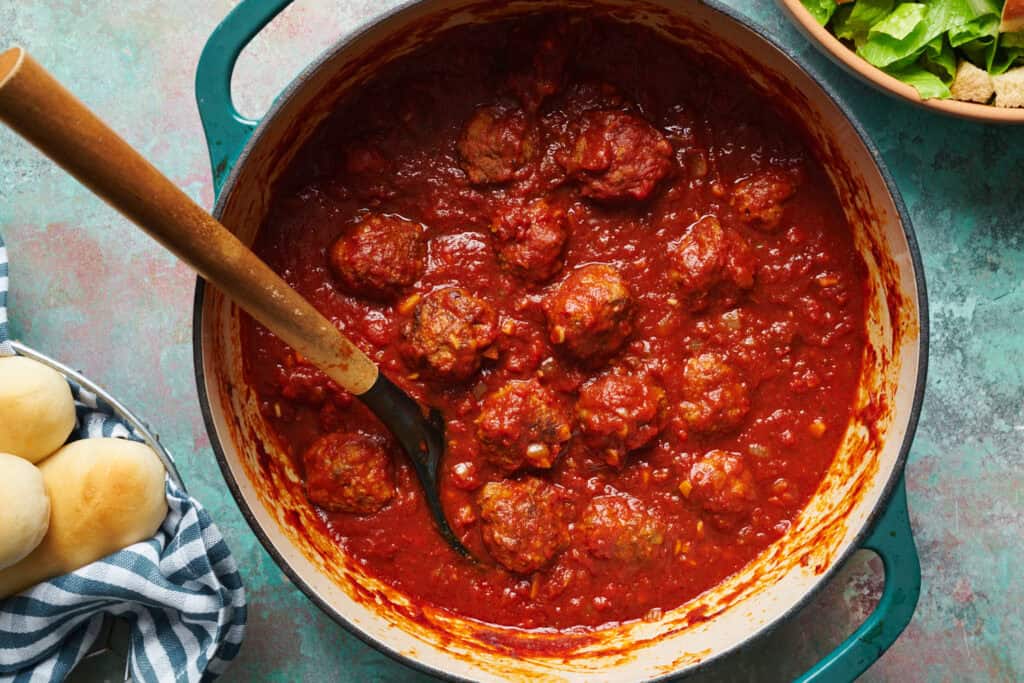 Overhead view of meatballs in a large dutch oven with zesty marinara sauce