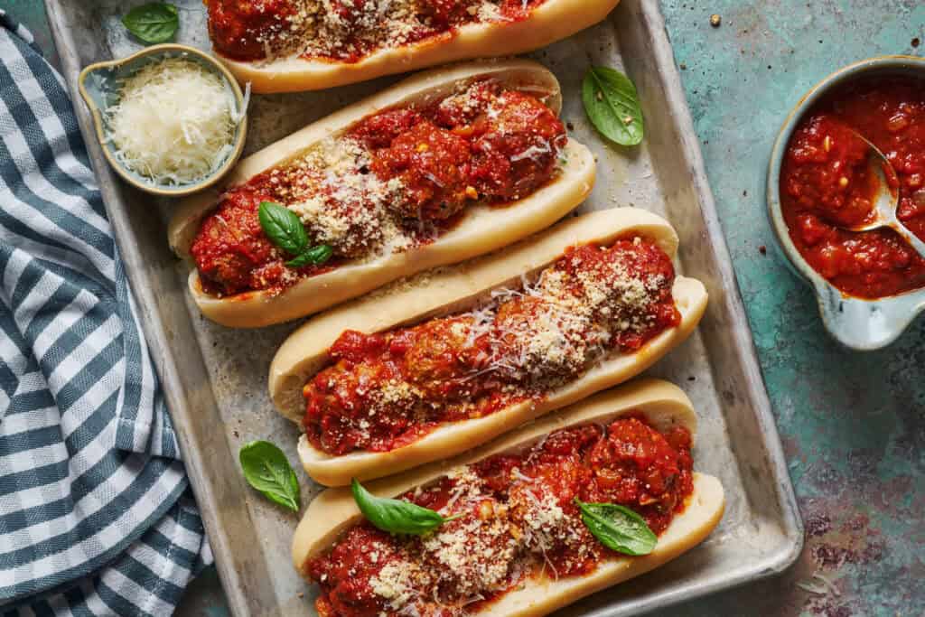 Overhead view of meatball subs with marinara, basil and parmesan cheese.