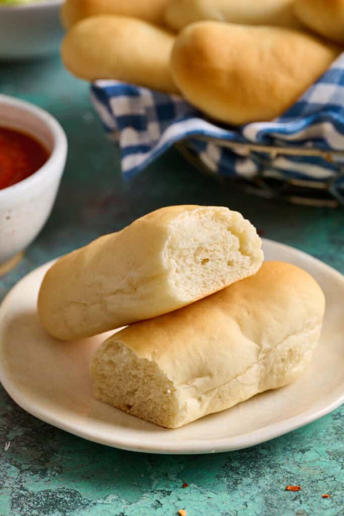 Side view of sourdough discard breadstick cut in half to show interior with a side of marinara sauce and salad.