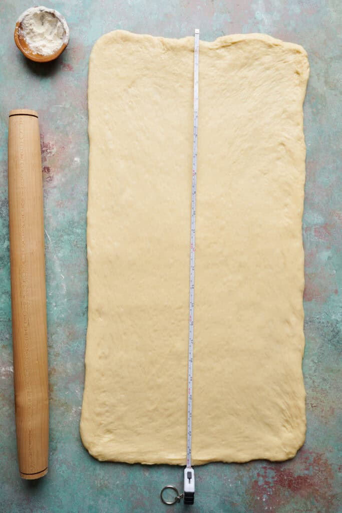 Dough rolled out onto a work surface and measured with a measuring tape