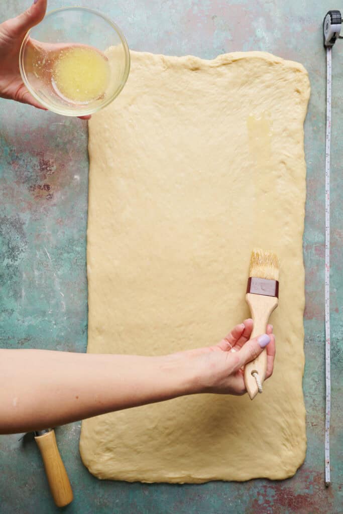 spreading butter onto rolled dough for cinnamon rolls