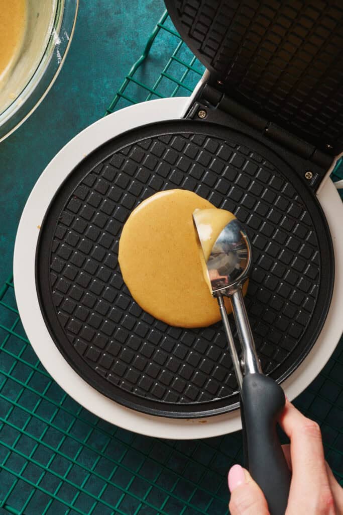 Overhead view putting waffle cone batter onto a waffle cone maker