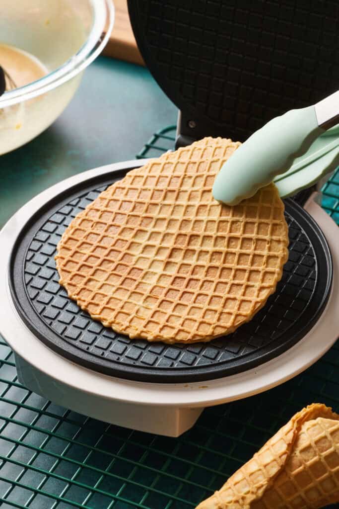 Taking a waffle off a waffle cone maker to make a waffle cone