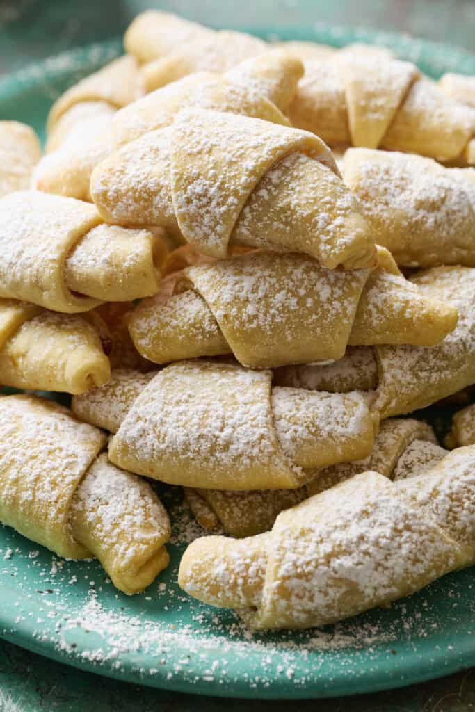 a stack of kifle cookies covered in powdered sugar