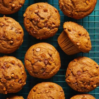 overhead view of fresh baked sourdough pumpkin muffins on a green surface and cooling rack