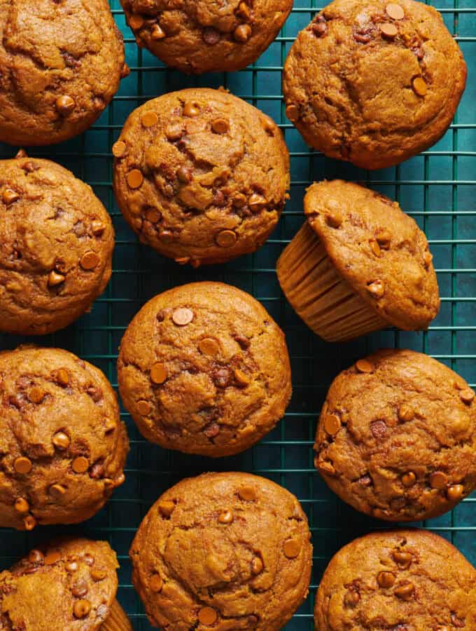 overhead view of fresh baked sourdough pumpkin muffins on a green surface and cooling rack