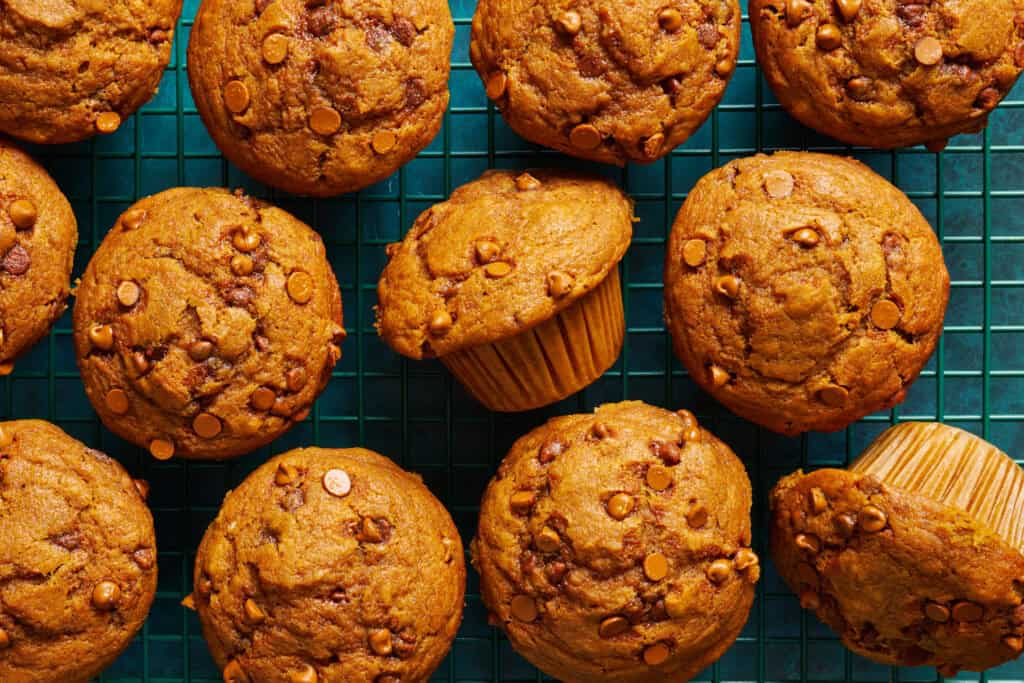 overhead view of pumpkin sourdough muffins on a green cooling rack and background