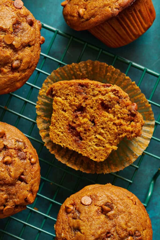 overhead of muffins on a cooling rack, one sliced in half to show how moist and fluffy it is