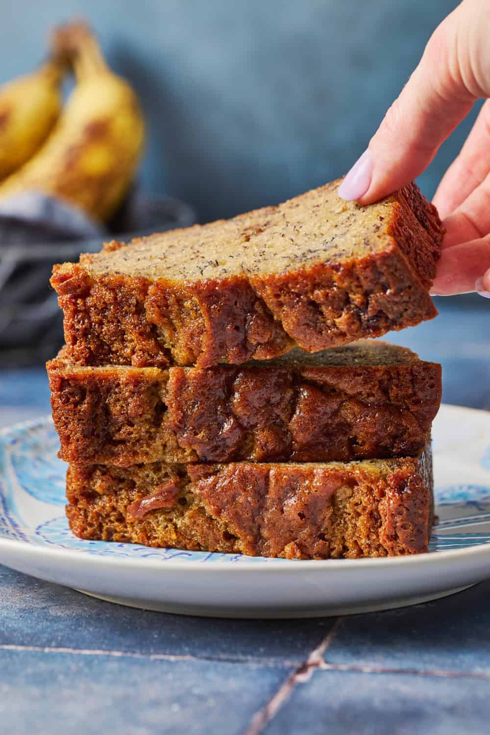 stack of slices of sourdough banana bread with one being lifted off the top