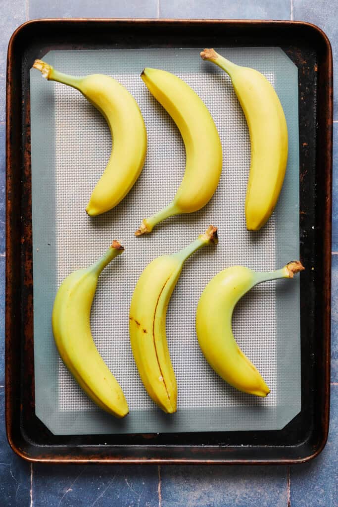 unripe bananas on a baking sheet