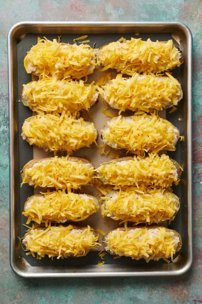 potatoes filled with tuna and potato and topped with cheese ready to bake on a sheet tray