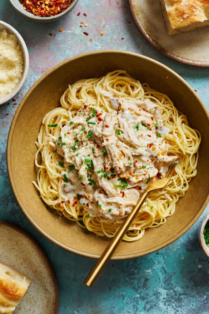 slow cooker angel chicken pasta with creamy sauce in a bowl with a fork