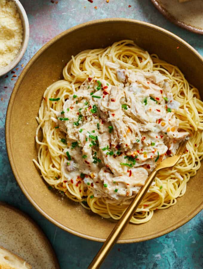 overhead view of a bowl of angel hair pasta topped with creamy chicken in a white sauce