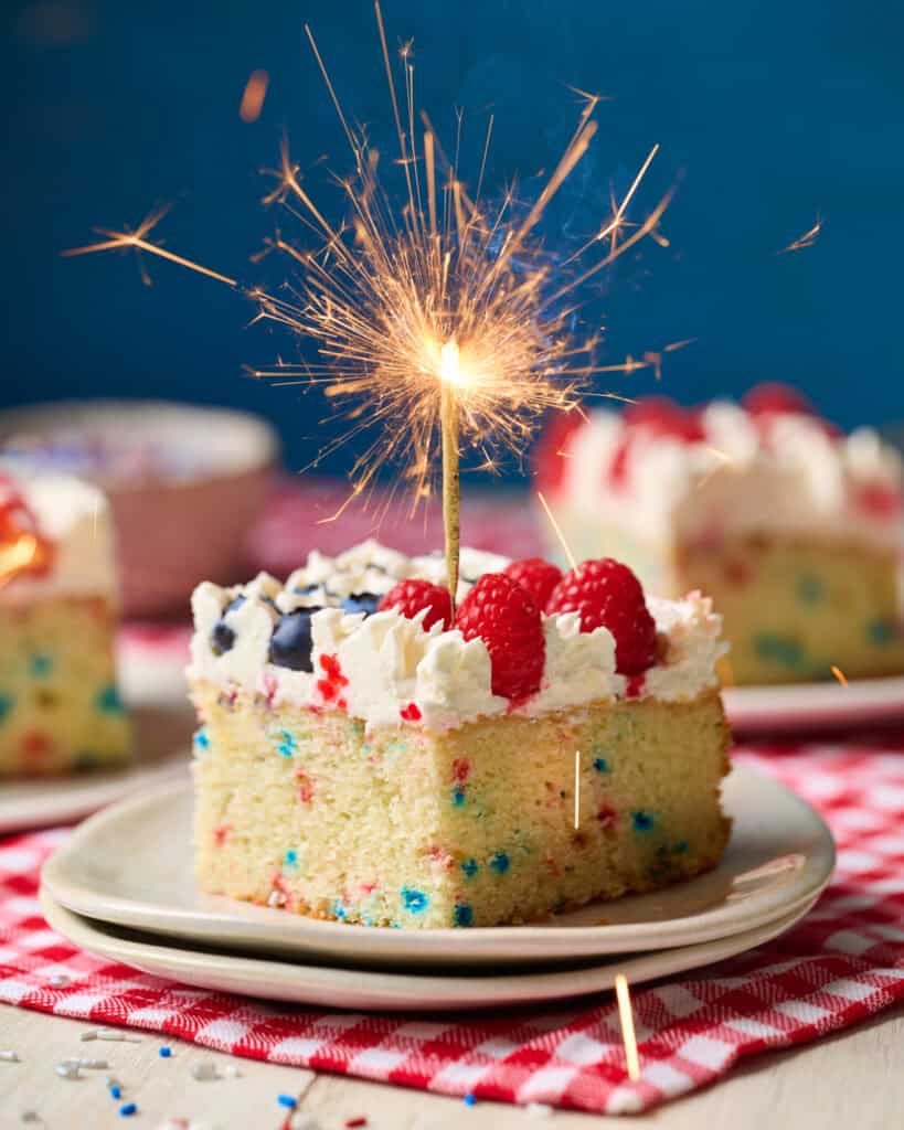 slice of flag cake with a gold sparkler that's bursting with sparks