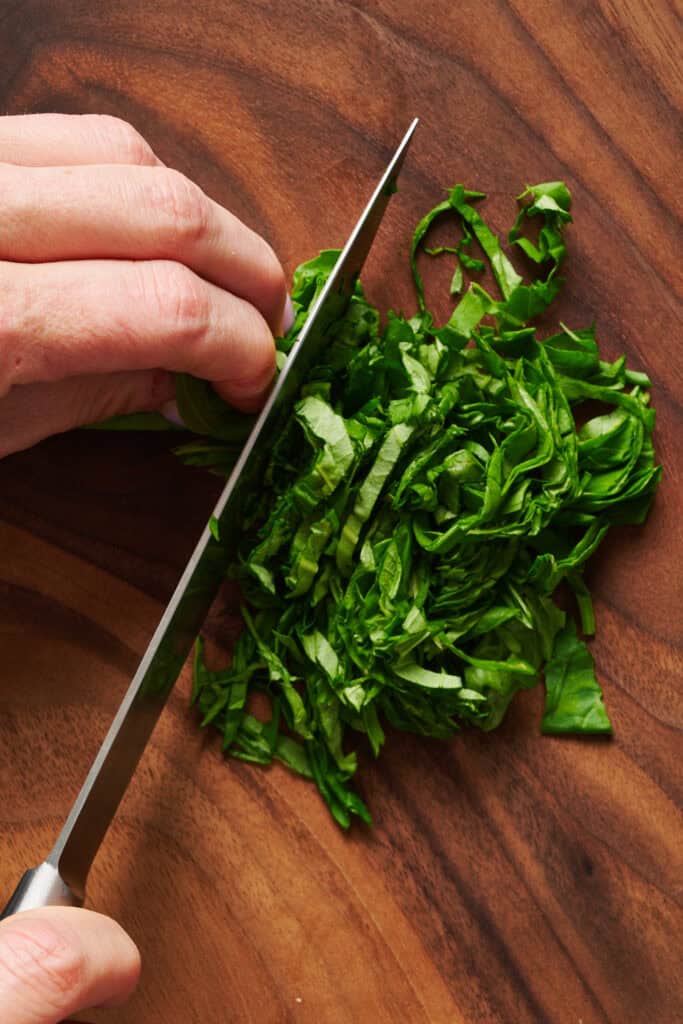 basil leaves being sliced for chiffonade