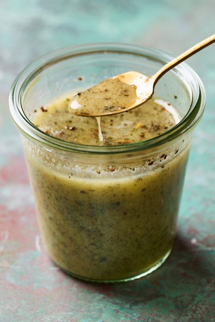 salad dressing in a jar with basil, dijon, vinegar and oil