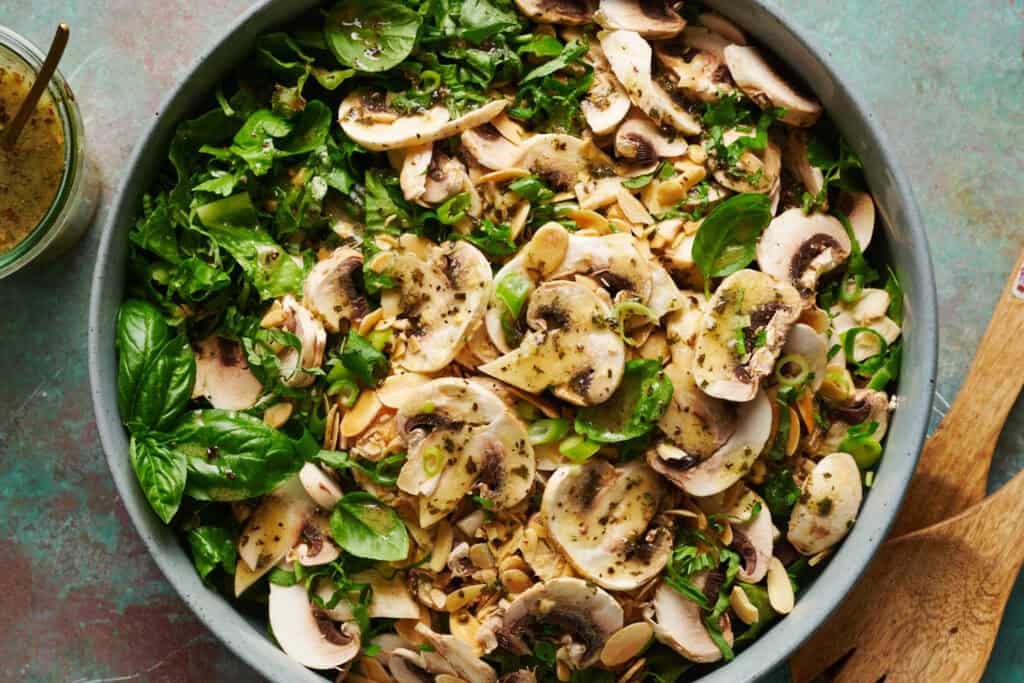 overhead view of a bowl of salad with mushrooms and fresh basil