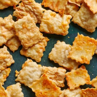 Overhead view of sourdough discard crackers scattered on a green surface