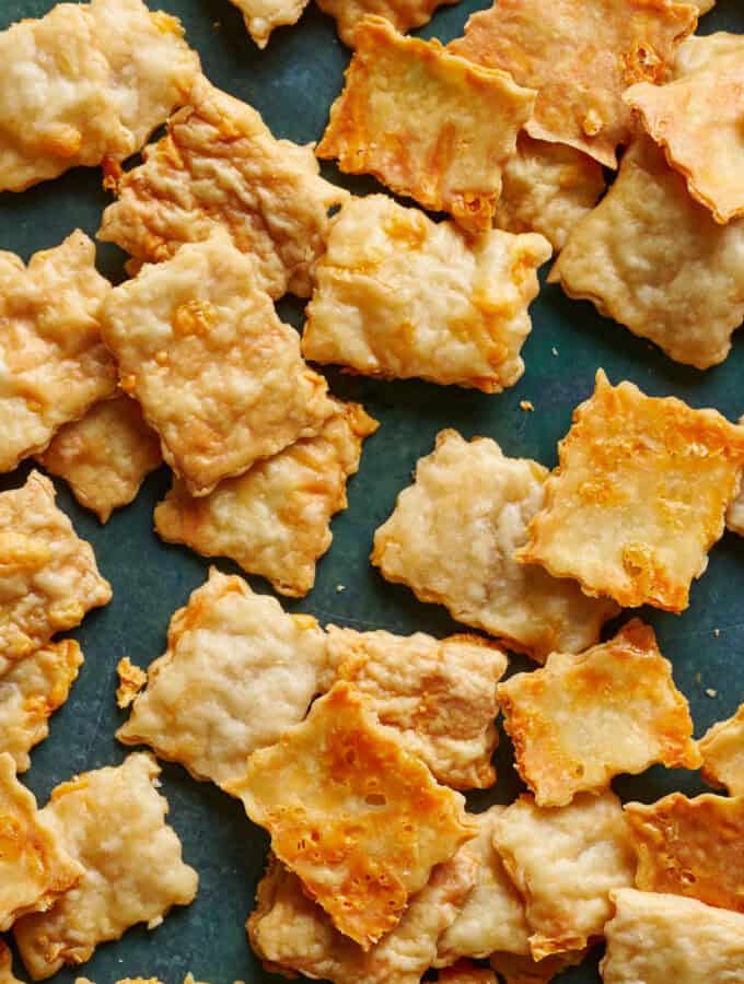 Overhead view of sourdough discard crackers scattered on a green surface