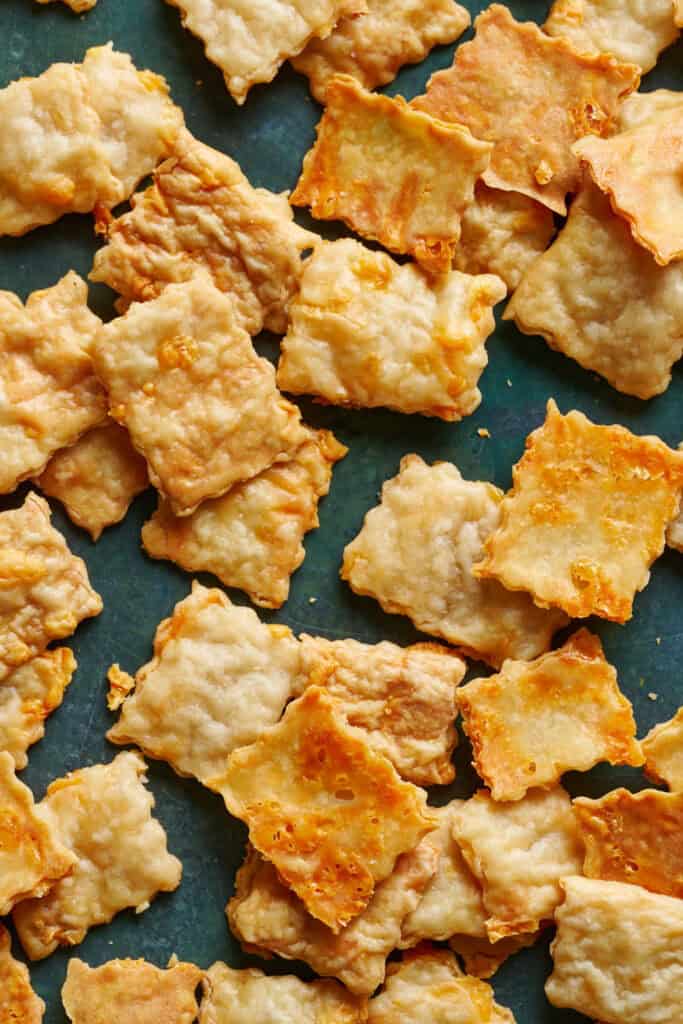 Overhead view of sourdough discard crackers scattered on a green surface